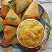 Apple chutney in bowl by samosas.