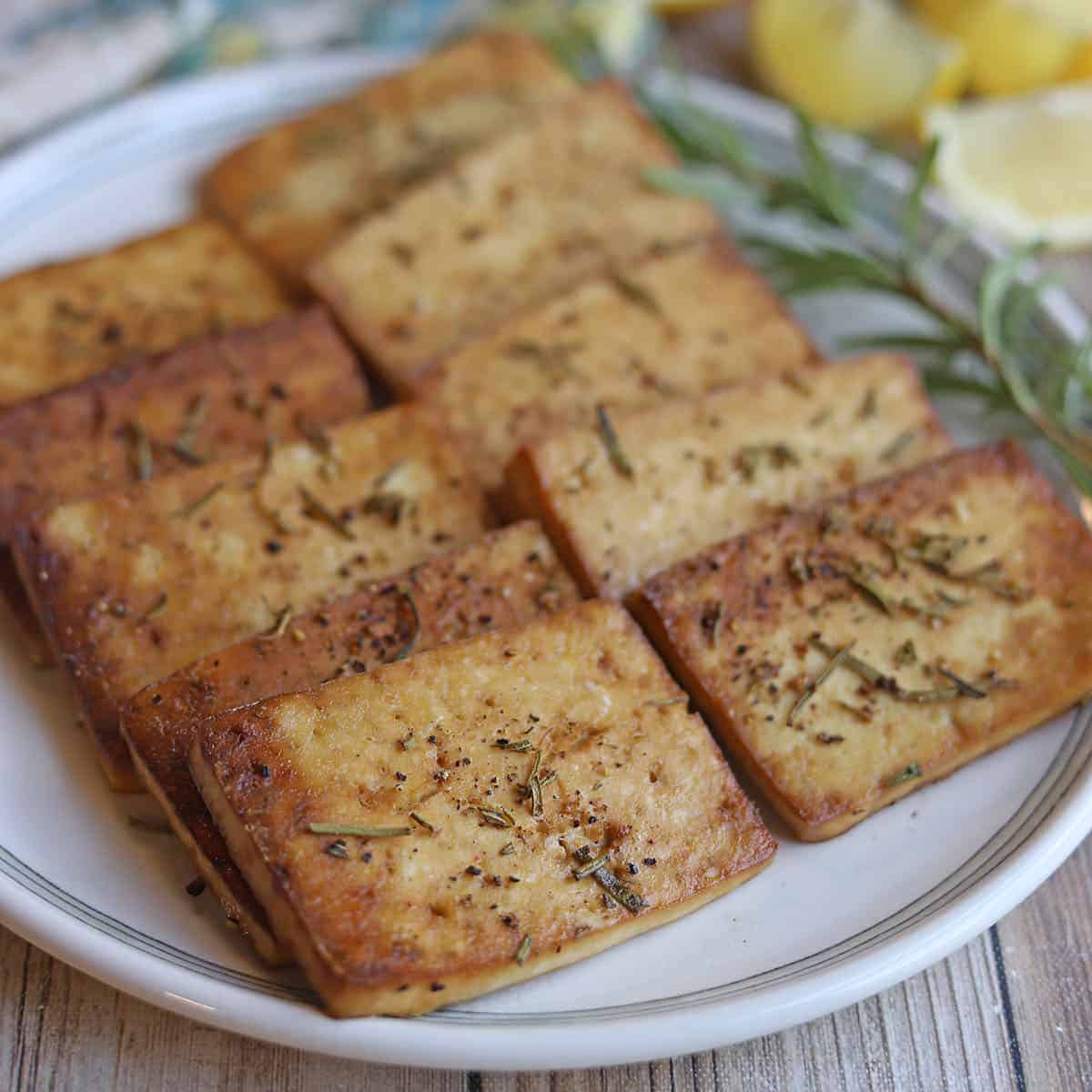 Slices of baked lemon rosemary tofu on platter.