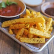 Pile of crispy air fried polenta fries on tray with marinara dipping sauce.
