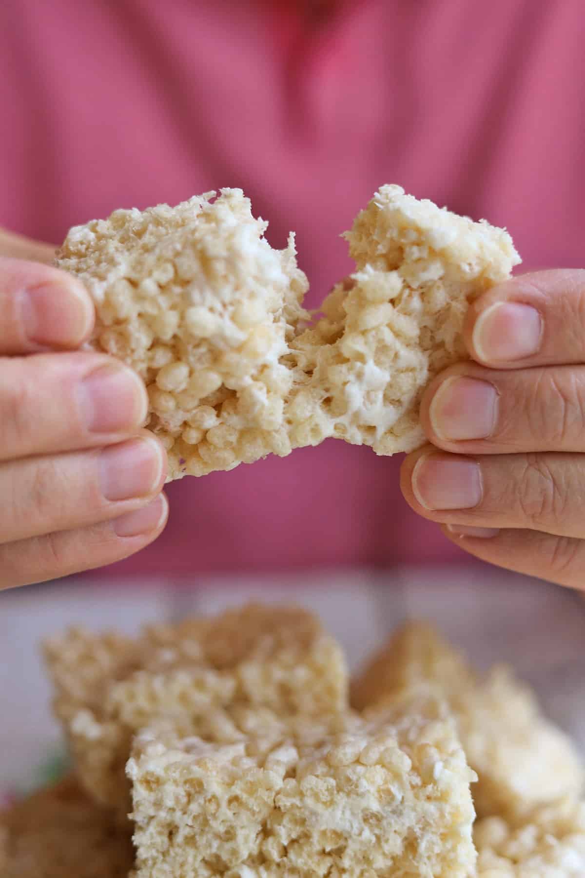Hands pulling apart gooey vegan rice crispy treats.