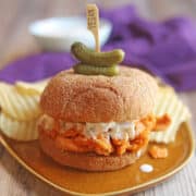 Buffalo Soy Curls sandwich with vegan blue cheese dressing on orange plate.