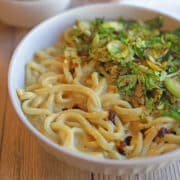 Cheesy vegan udon noodles with browned Brussels sprouts in bowl.