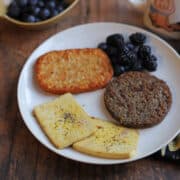 Eggy tofu slices on plate with hashbrown patty, berries, and vegan sausage.