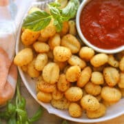 Pillowy air fried gnocchi on platter with basil and marinara dipping sauce.