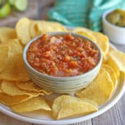 Oven roasted tomato salsa surrounded by tortilla chips on plate.