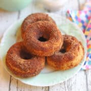 Stack of baked vegan cinnamon donuts on green plate.