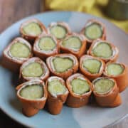 Vegan ham, cream cheese, and pickle roll-ups on plate.