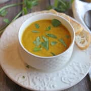 Kabocha squash soup with coconut milk in bowl by crostini.