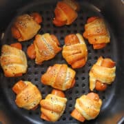 Vegan pigs in a blanket in air fryer basket.