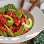 Avocado caprese salad with basil in bowl.