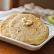Vegan arepas with dollop of non-dairy butter on plate.