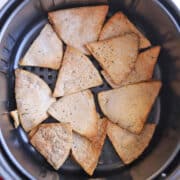 Crispy seasoned pita chips in the air fryer basket.