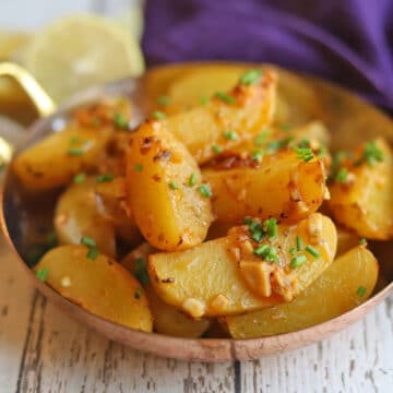 Greek lemon potatoes with chives and garlic in serving dish.