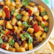 Juicy peach salsa with black beans and cilantro in bowl.
