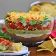 Vegan 7 layer dip in glass bowl by tortilla chips.