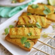 Grilled tofu satay on plate with peanut & cilantro garnish.