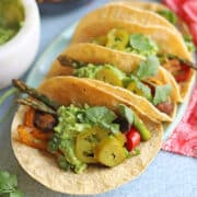 Mushroom, bell pepper, and asparagus fajitas in corn tortillas on platter.