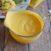 Creamy vegan hollandaise sauce in glass gravy boat.