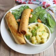 Crunchy vegan taquitos with jackfruit filling by spinach salad and pineapple salsa.