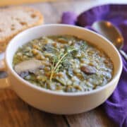 Double lentil mushroom barley soup in bowl garnished with fresh thyme.