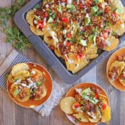 Barbecue jackfruit tacos with vegan cheese, avocado, and cilantro on a sheet pan by serving plates.