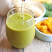 Pumpkin smoothie with kale in glass with straw.