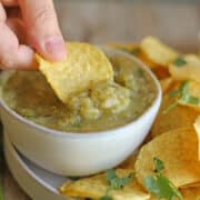 Tortila chip being dunked into salsa verde.