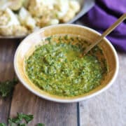 Cilantro chimichurri sauce without parsley in yellow bowl with spoon.