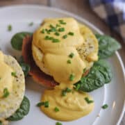 Vegan eggs benedict on plate with eggy tofu, seitan ham, spinach, and a luxurious cashew hollandaise.