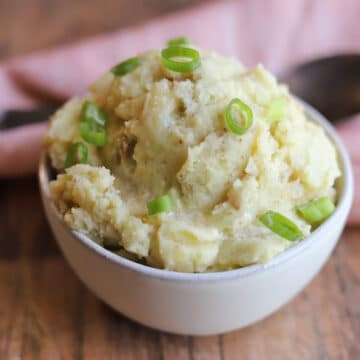 Mustard mashed potatoes in bowl, garnished with green onions.