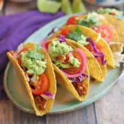 Vegan tempeh taco platter with guacamole and cherry tomatoes.