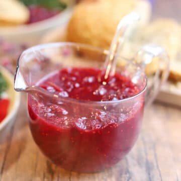 Cranberry sauce with orange juice in serving pitcher with spoon.