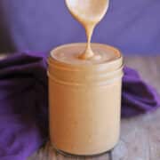 Close-up peanut sauce for spring rolls dripping into jar.