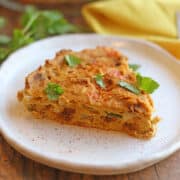 Slice of vegan, egg-free frittata on plate with cilantro garnish.