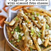 Text overlay: cadryskitchen.com, vegan poutine with almond feta cheese. Baked fries covered in meatless gravy and dairy-free cheese.