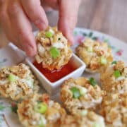 Easy vegan crab rangoon with green onions being dipped into sweet and sour sauce.