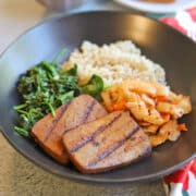 Grilled bulgogi tofu in bowl with vegan kimchi, garlicky spinach, and brown rice.