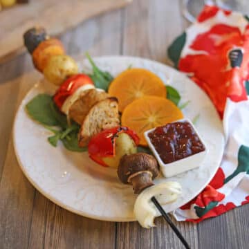 Skewer on plate with mushroom, onion, seitan, bell pepper, and bread.