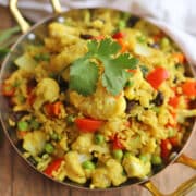 Mixed vegetable rice seasoned with turmeric and ginger in skillet.