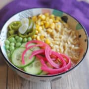 Vegan ramen with tahini broth topped with peas, corn, cucumbers, pickled jalapenos, and pickled red onions.