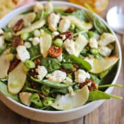 Fall salad in bowl with vegan feta, candied pecans, and roasted apple slices.