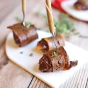 Vegan bacon wrapped dates on small plate.