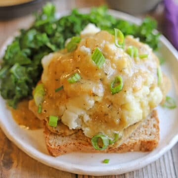 Vegan hot open faced sandwich with mashed potatoes, gravy, and vegan turkey on wheat bread.
