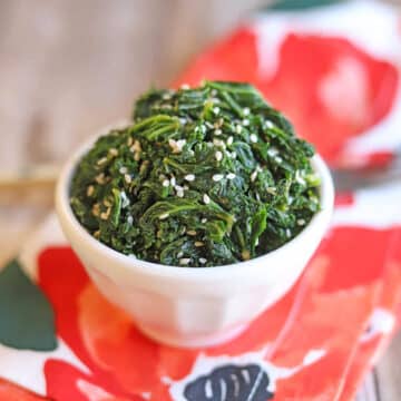 Sesame kale in white bowl on flowered napkin.