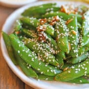 Stir-fried sugar snap peas with garlic, ginger, an sesame seeds on plate.