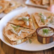 Vegan pierogi quesadilla wedges on plate with non-dairy yogurt ranch dipping sauce.