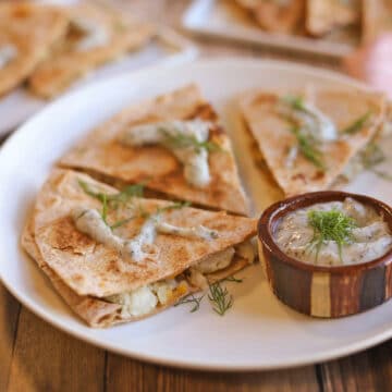 Vegan pierogi quesadilla wedges on plate with non-dairy yogurt ranch dipping sauce.
