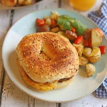 Vegan bagel breakfast sandwich on plate with potato hash.