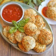 Air fryer ravioli on platter with tomato dipping sauce.