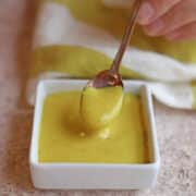 Spoon scooping out vegan honey mustard.
